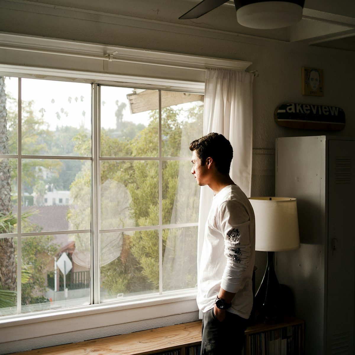 A man standing quietly at a window in morning light